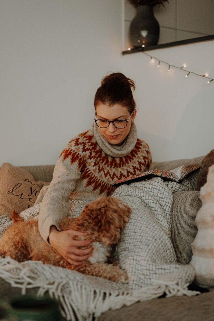 Simone Schuh liest entspannt auf Couch mit Hund – vlygge Living verbindet Veganismus mit Gemütlichkeit