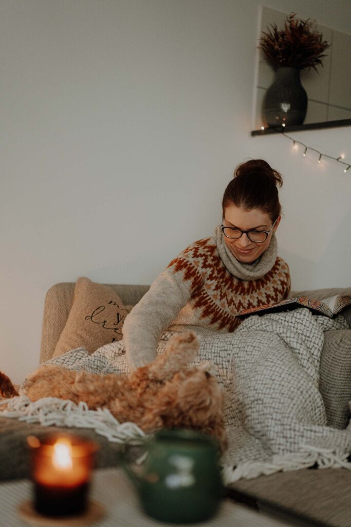 vlygge Living Coach kuschelt sich mit Hund auf Sofa ein – vlygge living hilft veganes Leben hyggelig gestalten